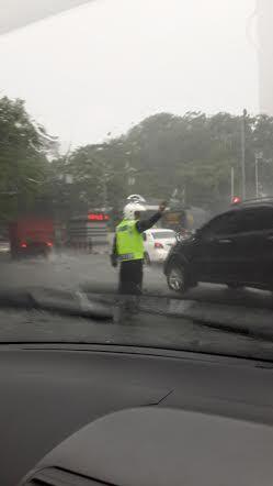 Luar Biasa! Di Tengah Hujan Badai Polisi ini Tetap Atur Lalin di HI 