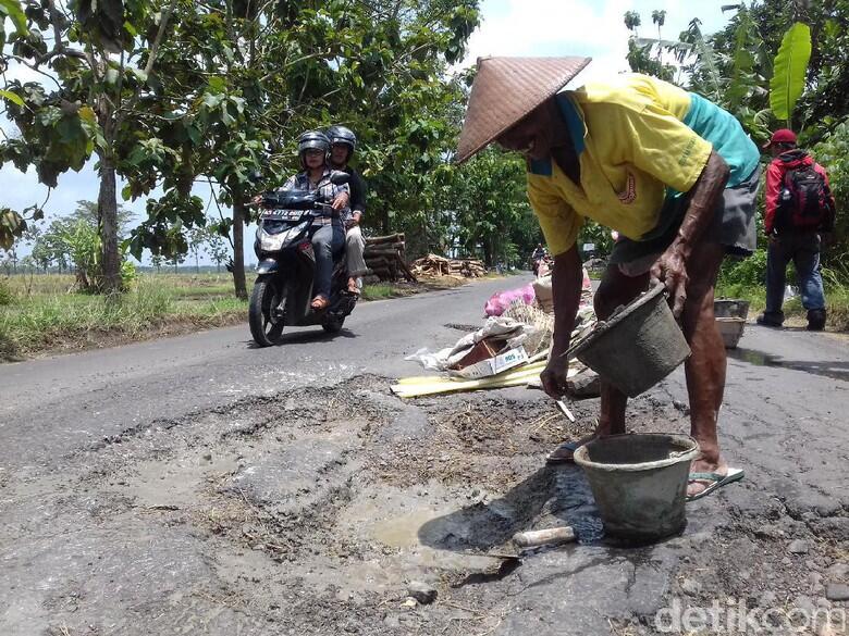 Begini Aksi Mbah Sadiyo Tambal Jalan Berlubang Sendirian