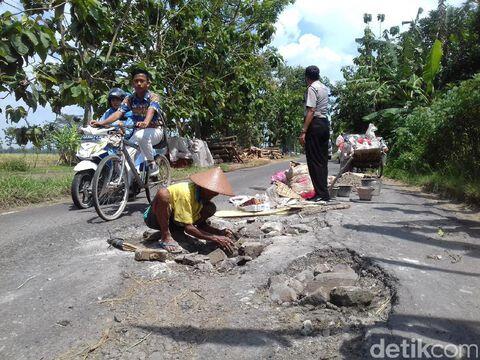 Begini Aksi Mbah Sadiyo Tambal Jalan Berlubang Sendirian