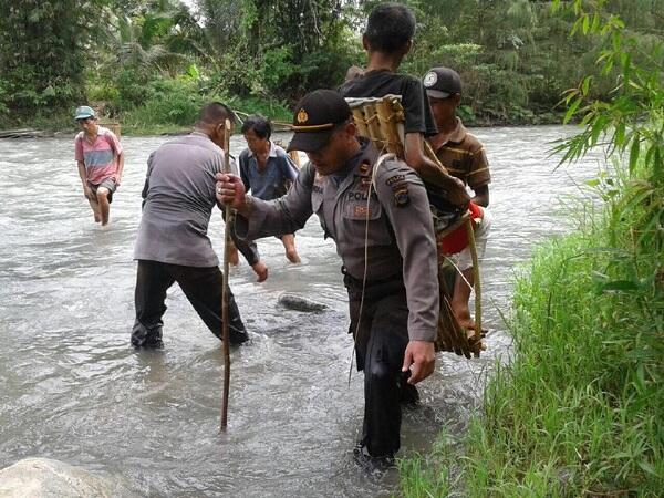 Salut, Pak Polisi Ini Gendong Warga yang Sakit di Pedalaman Sulteng