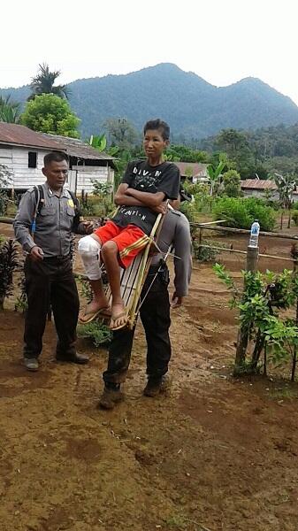 Salut, Pak Polisi Ini Gendong Warga yang Sakit di Pedalaman Sulteng