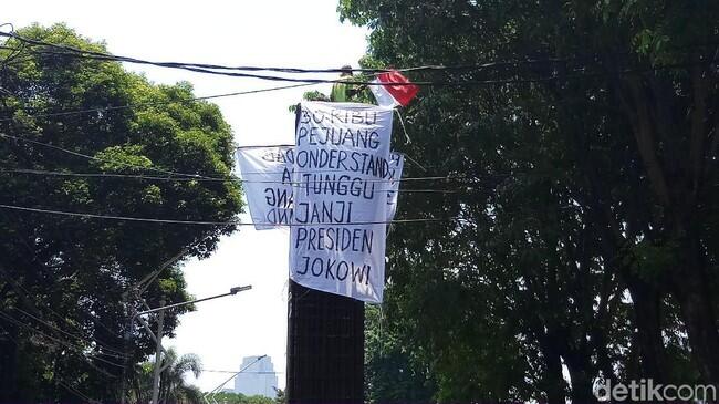Pria Ini Panjat Beton di Belakang DPR, Kibarkan Spanduk Tagih Janji Jokowi