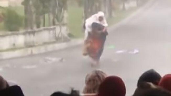 Pria Gendong Ibunya Berteduh dari Hujan Usai Salat Id
