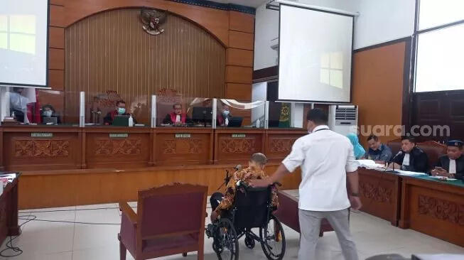 M Kece Kini Dibawa ke Sidang Pakai Kursi Roda dengan Kondisi Tangan Terborgol